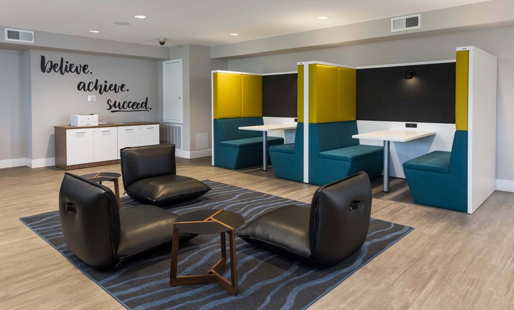 A room with a quote on the wall and a few chairs and tables.