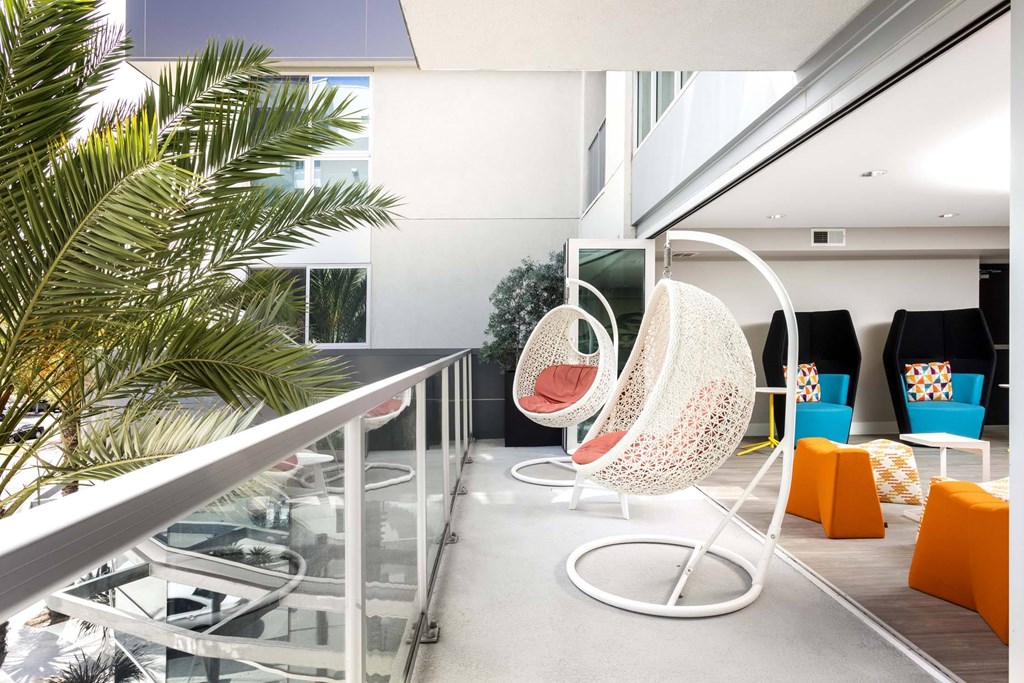 A white chair with a circular base and a white seat with a patterned design is in the foreground of the image.