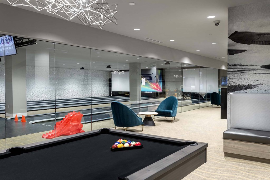 A pool table in a room with a glass wall and a TV mounted on the wall.