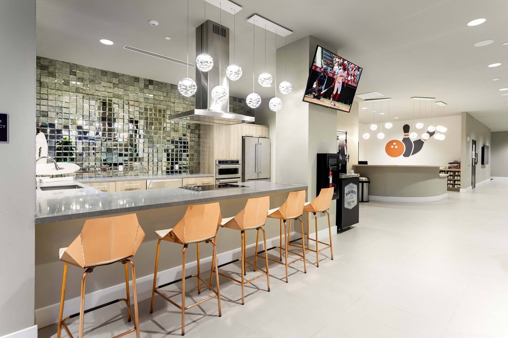 A modern bar with orange chairs and a stone wall in the background.