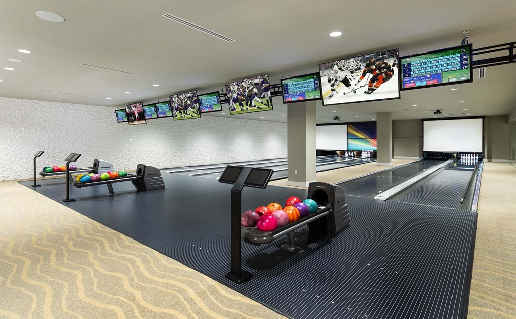 A bowling alley with multiple lanes and bowling balls on the racks.