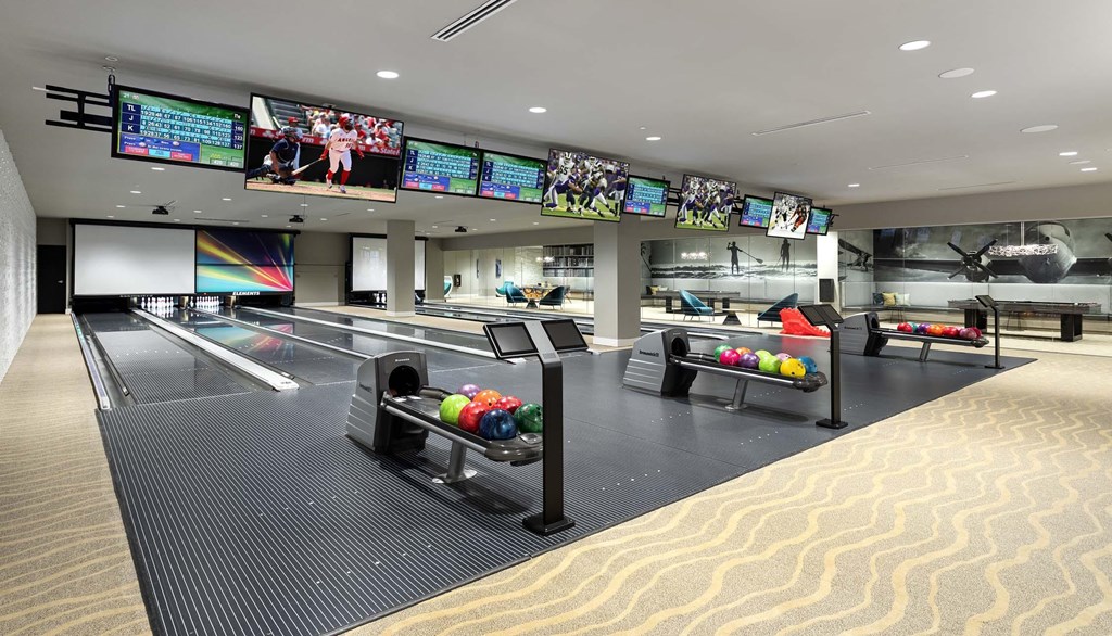 A bowling alley with multiple lanes and bowling balls on the counter.