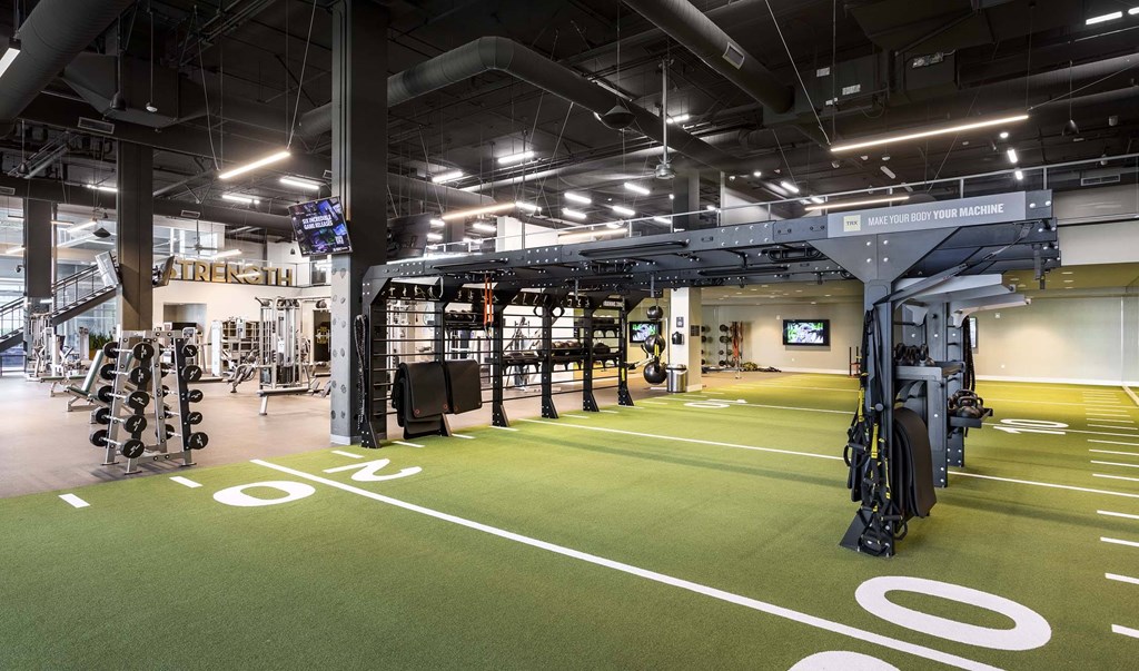 A gym with a green floor and a variety of equipment.