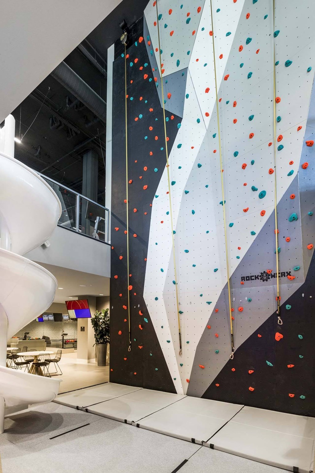 A climbing wall in a gym with a white rock climbing wall.