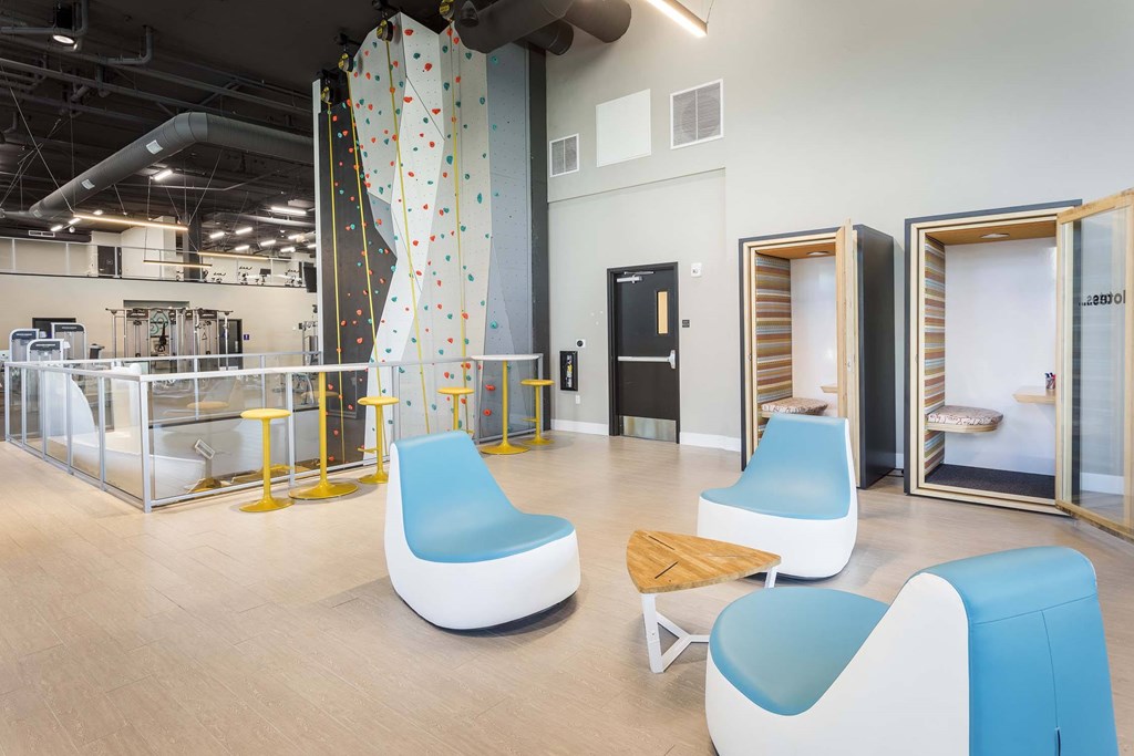 A room with a climbing wall and blue chairs.