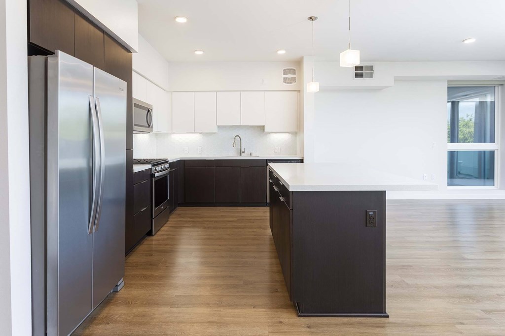A modern kitchen with dark wood floors and stainless steel appliances.