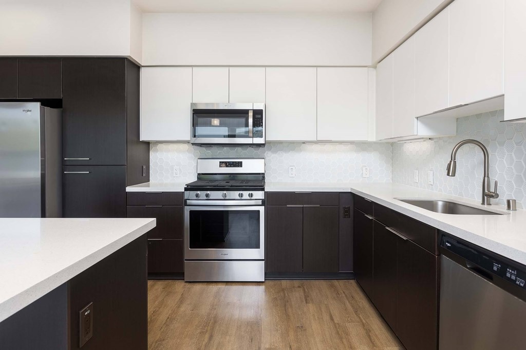 A modern kitchen with dark wood cabinets and stainless steel appliances.