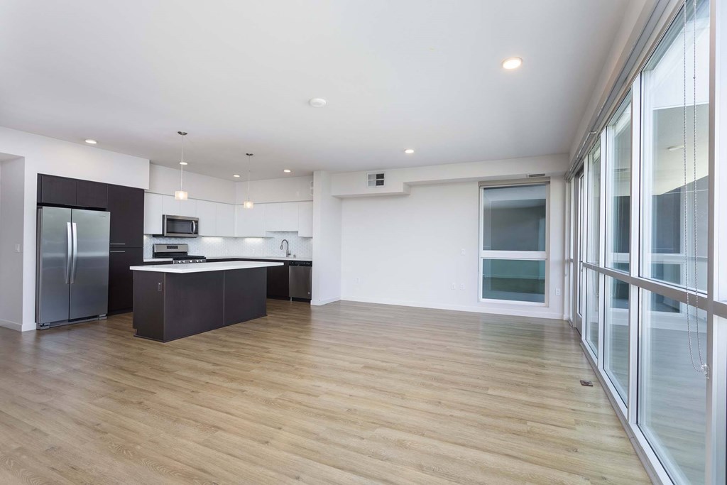 A kitchen with a refrigerator, sink, and stove.
