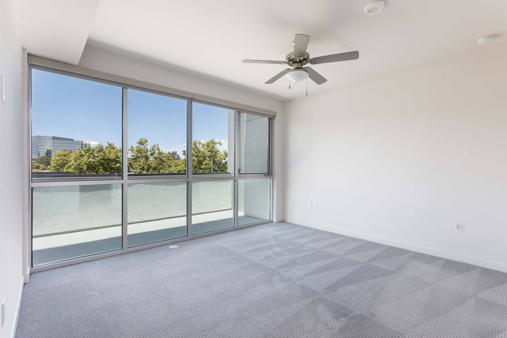 A room with a ceiling fan and sliding glass doors.