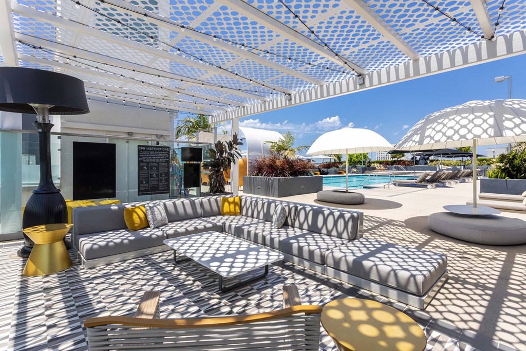 A sunny day at the poolside with a white canopy overhead.