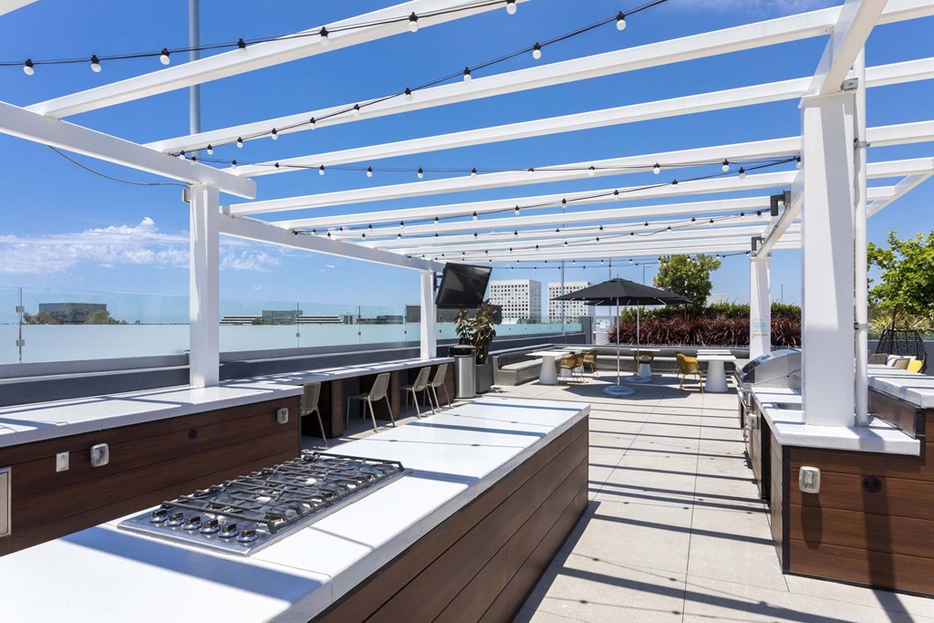 A rooftop patio with a grill and seating area.