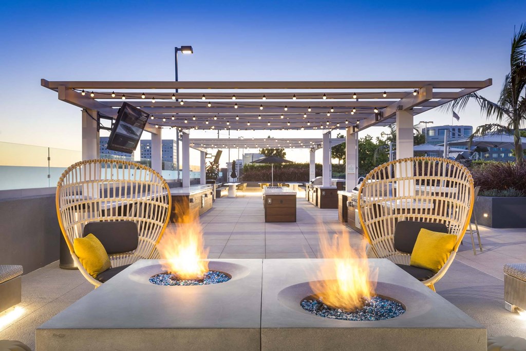 A patio with two fire pits and wicker chairs.