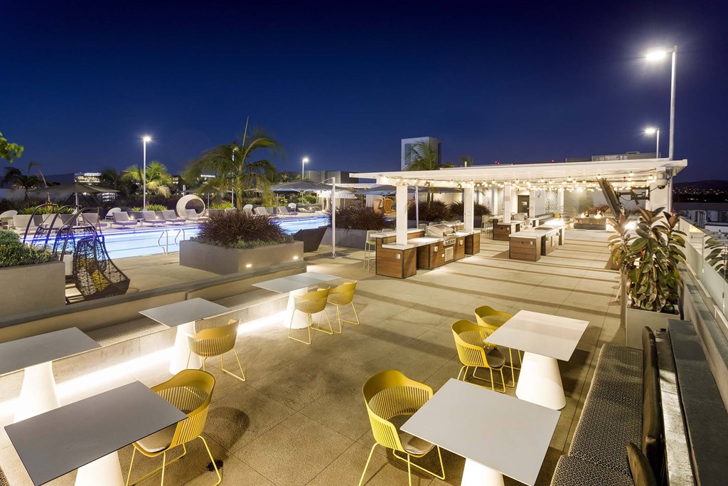 A rooftop patio with tables and chairs is lit up at night.
