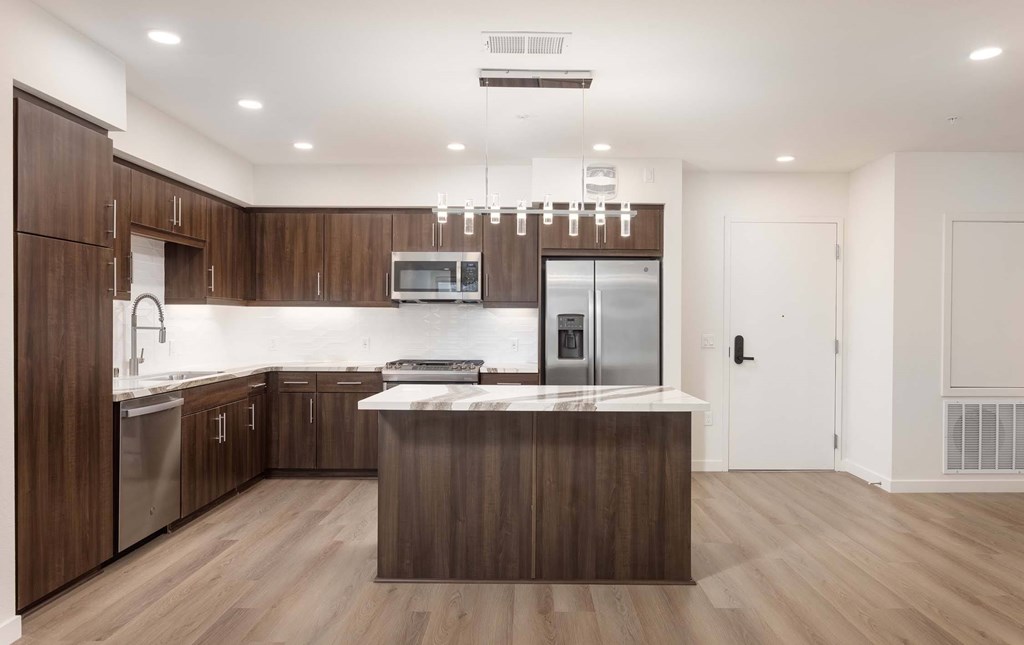 A modern kitchen with dark wood cabinets and stainless steel appliances.