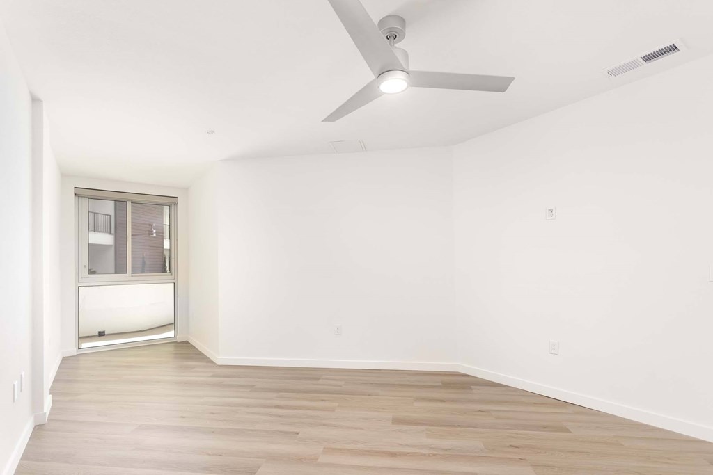 A room with a ceiling fan and a window.