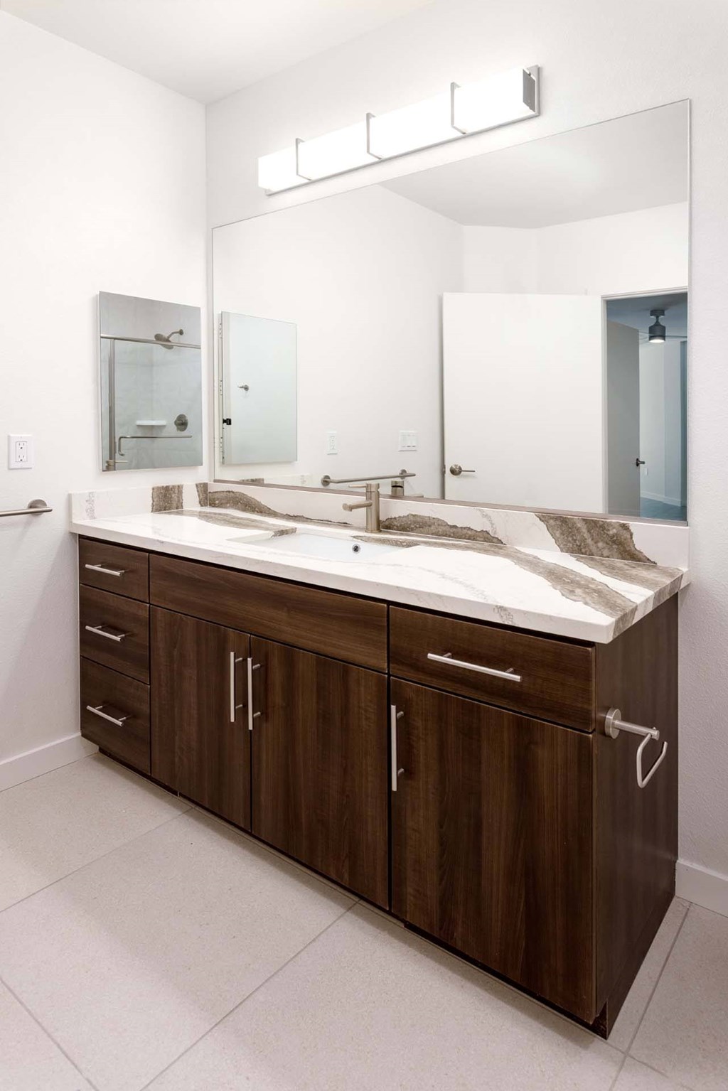 A bathroom with a brown vanity and a white countertop.
