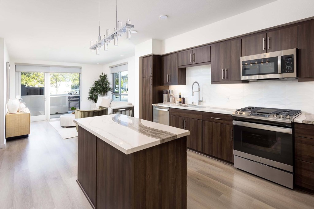A modern kitchen with dark wood cabinets and stainless steel appliances.
