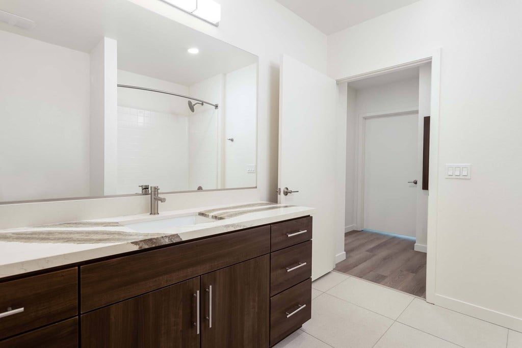 A bathroom with a sink, mirror, and wooden cabinets.