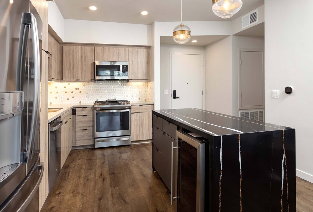 A modern kitchen with a black marble island and stainless steel appliances.