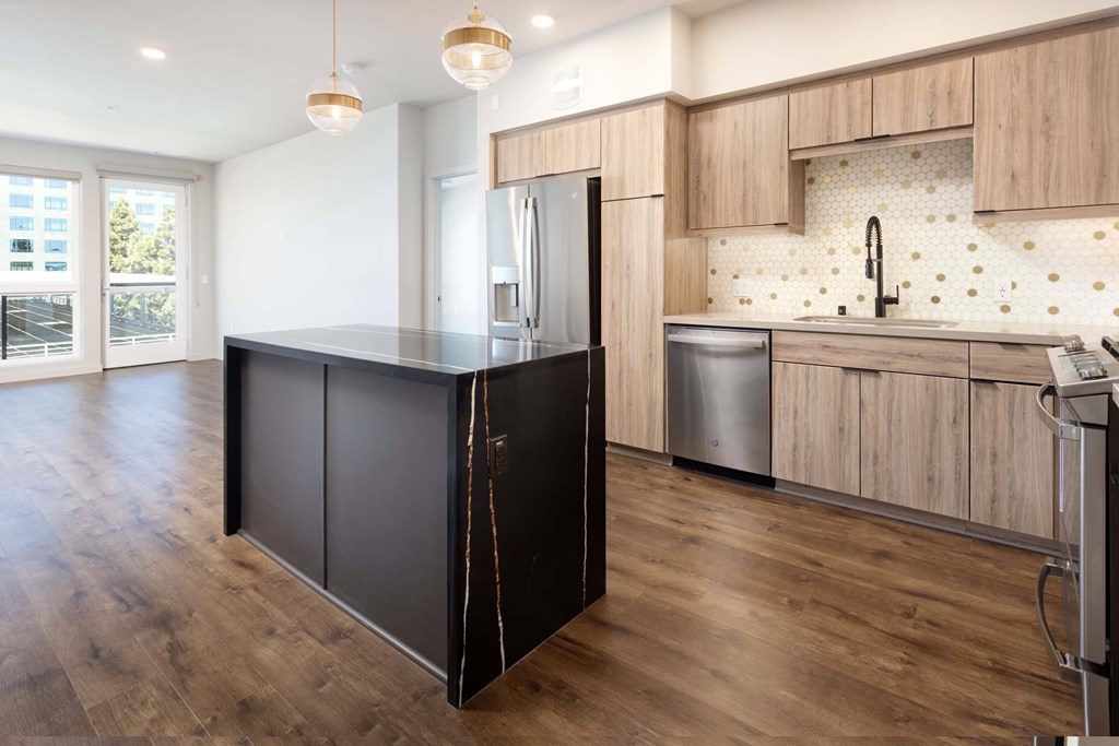 A kitchen with a black refrigerator and wooden cabinets.