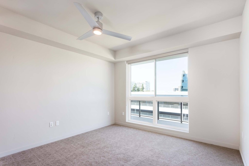 A room with a ceiling fan and a large window overlooking a bridge.