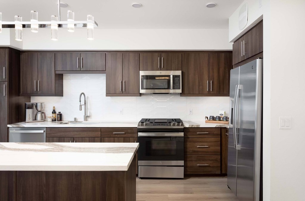 A modern kitchen with dark wood cabinets and stainless steel appliances.
