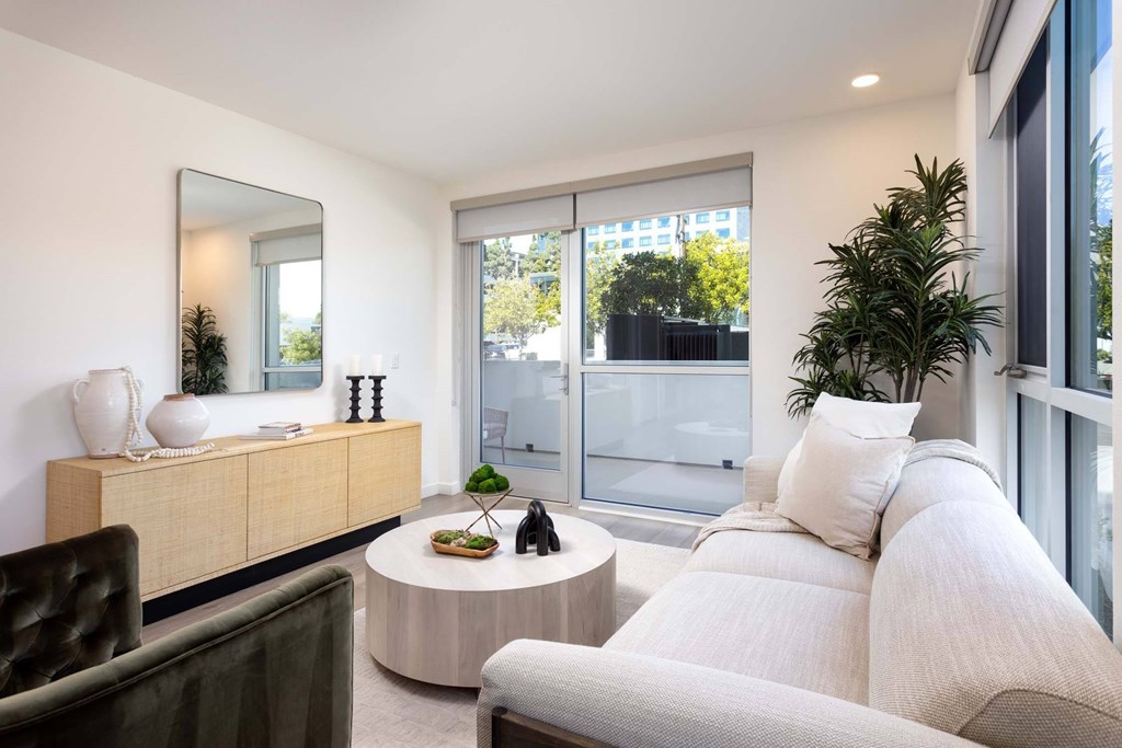 A living room with a white couch and a round table with a plant on it.