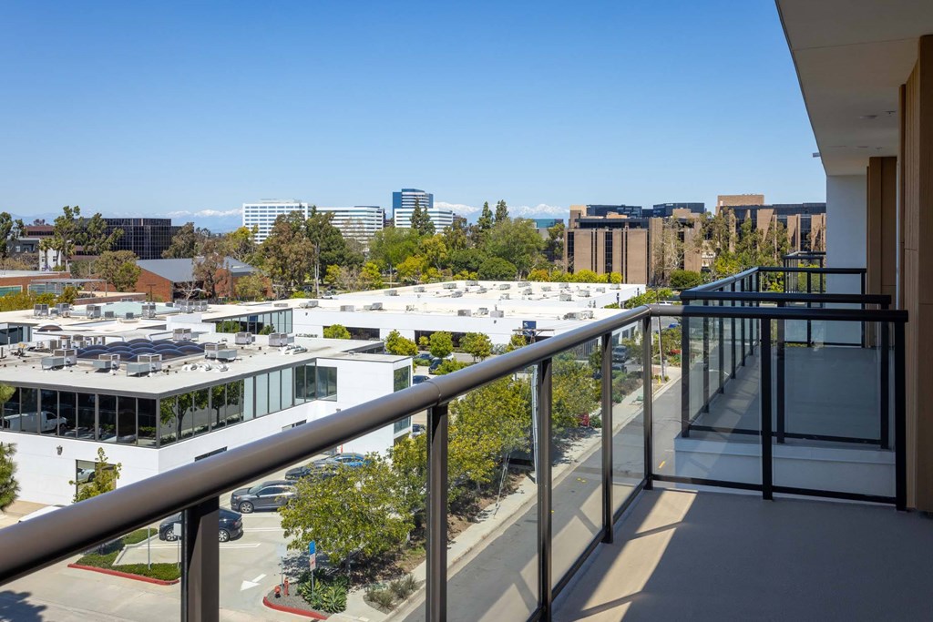 A balcony overlooks a parking lot and buildings.