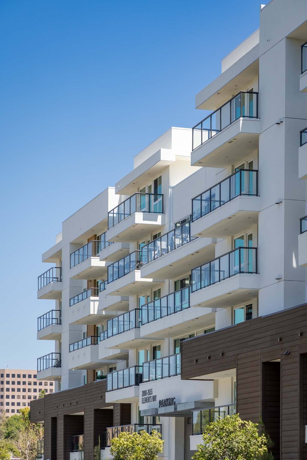 A white residential building with balconies and a black awning.