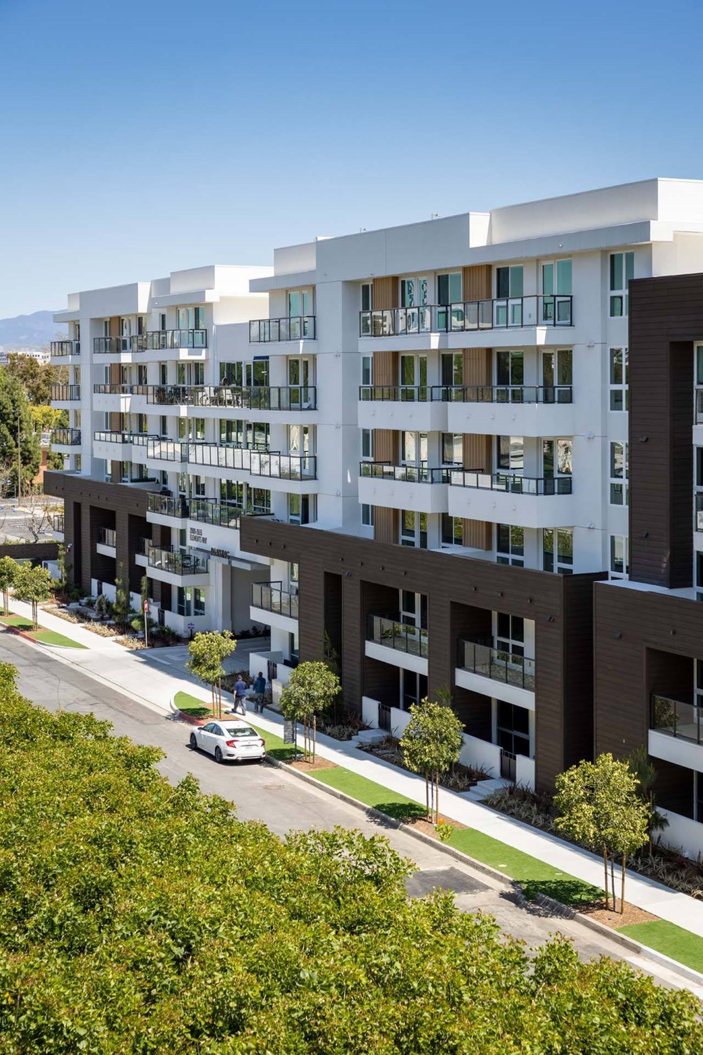 A modern apartment building with a car parked on the street in front.
