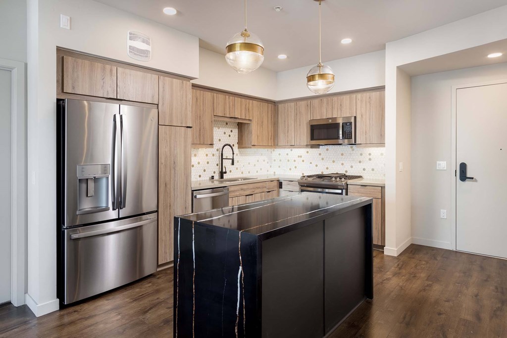 A modern kitchen with a black island and stainless steel appliances.