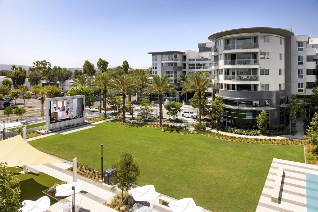 A large screen is mounted on a wall in a park.