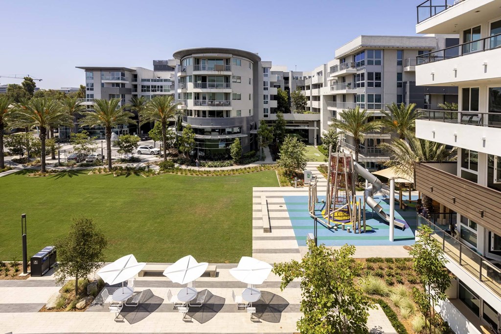A modern apartment complex with a pool and outdoor seating area.