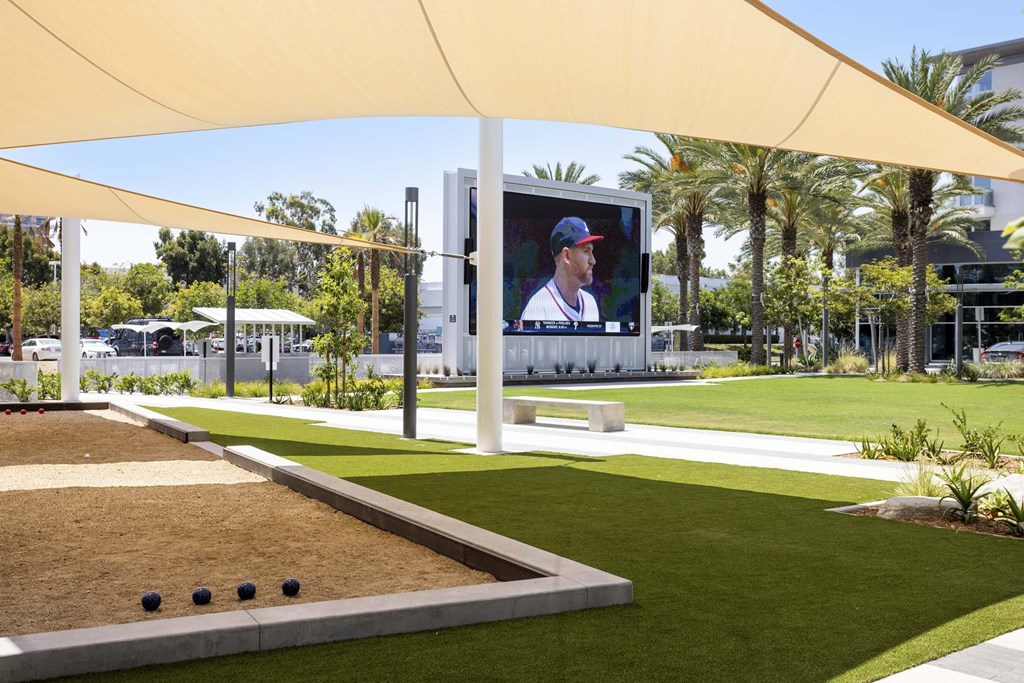 A large screen is set up outside with a baseball game on it.