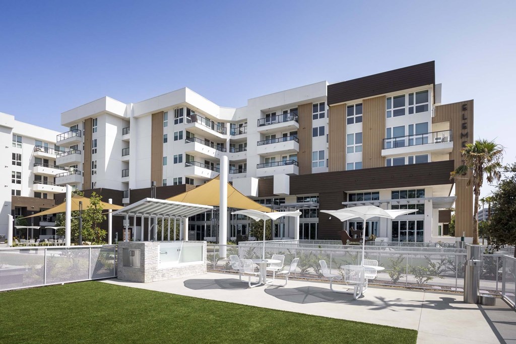 A modern building with a white fence and a grassy area in front.