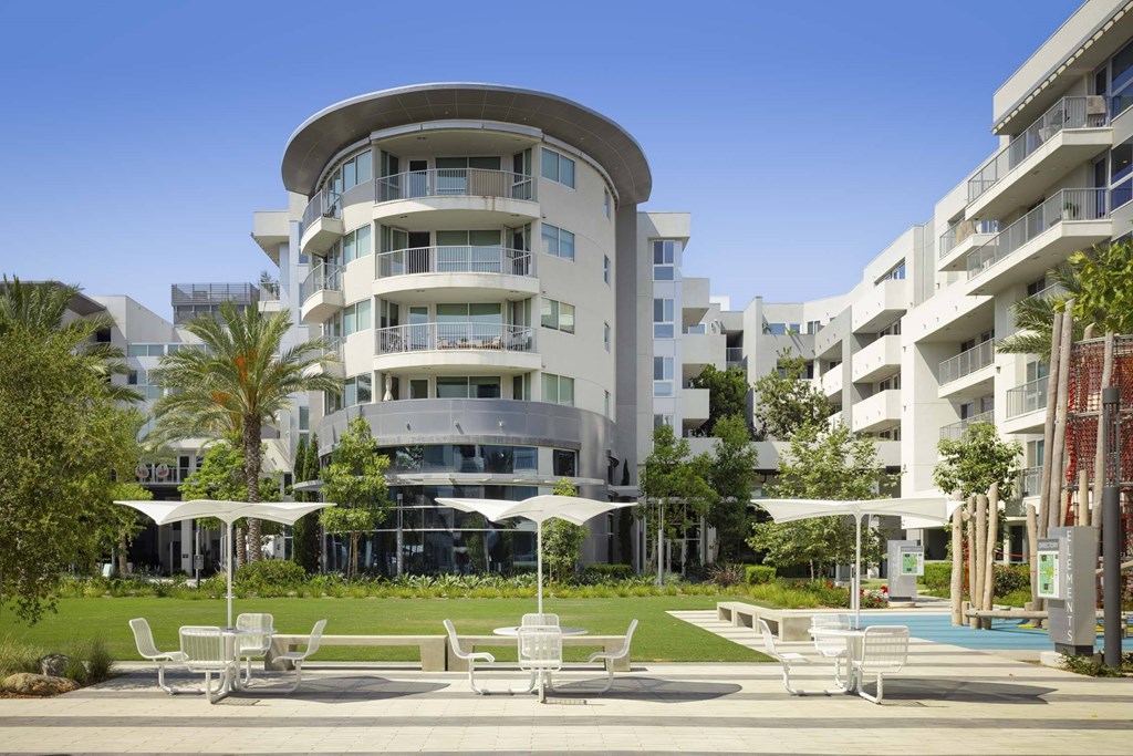 A white building with a curved design and a pool in front.