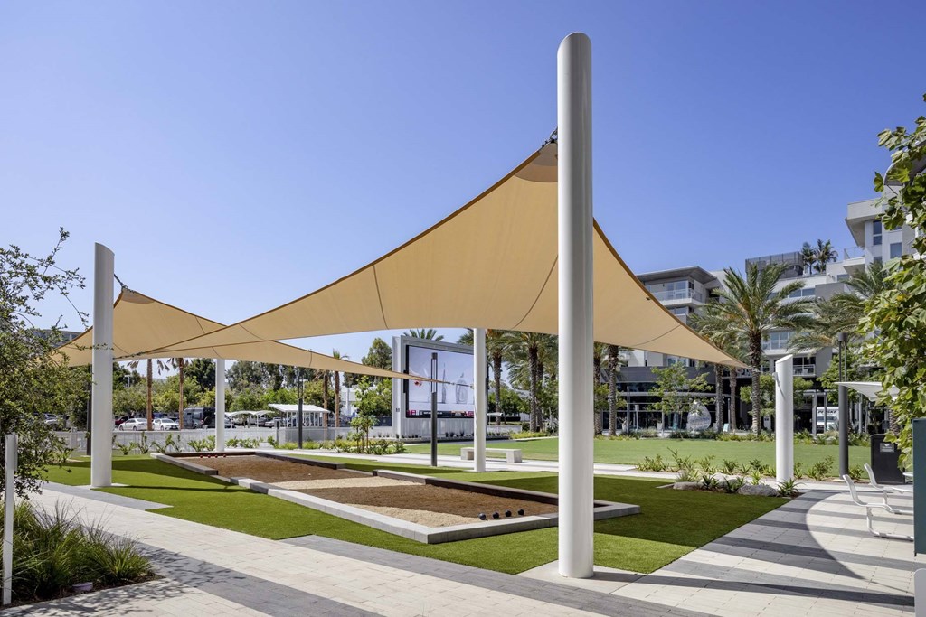 A large beige shade structure is over a grassy area.