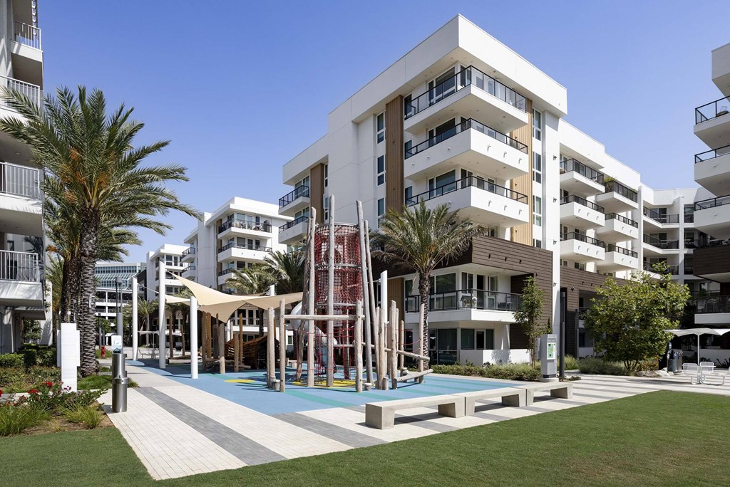 A modern apartment complex with a pool and a playground.