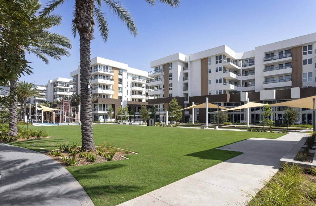 A sunny day at a modern apartment complex with a well-maintained lawn and walking paths.