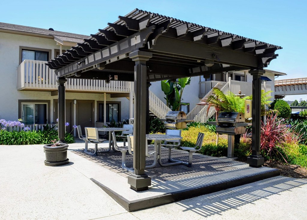 A patio with a table and chairs under a pergola.at La Jolla Canyon Apartments, San Diego