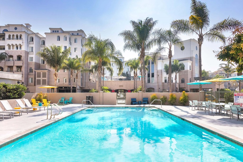 A swimming pool surrounded by palm trees and lounge chairs. at La Jolla Crossroads Apartments, San Diego