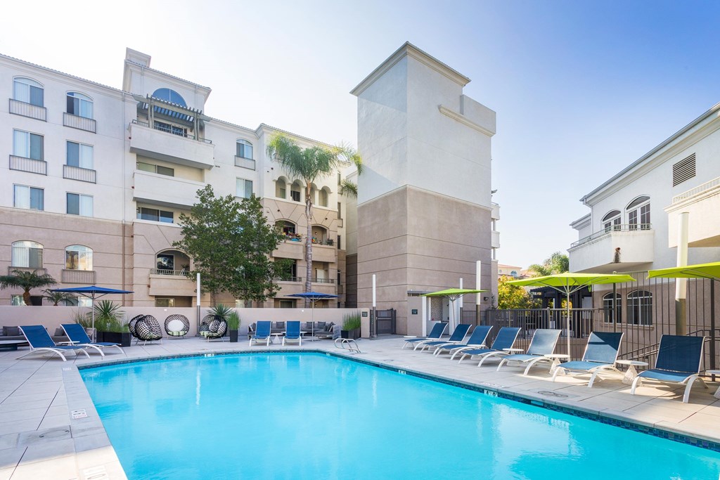 A pool surrounded by lounge chairs in front of a building. at La Jolla Crossroads Apartments, San Diego, CA, 92122