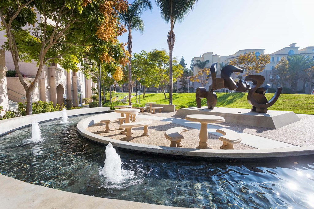 A fountain in the middle of a park with a sculpture in the background. at La Jolla Crossroads Apartments, California
