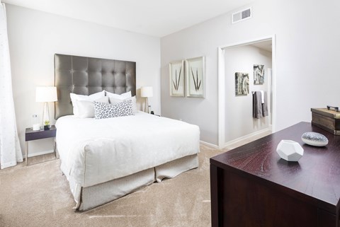 Bedroom with tufted headboard and ensuite bathroom at La Jolla Crossroads Apartments, San Diego, California