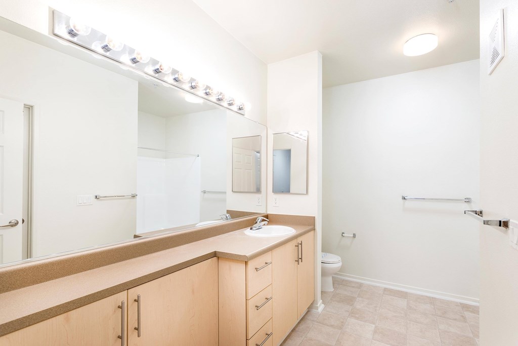 A bathroom with a sink, mirror, and toilet. at La Jolla Crossroads Apartments, San Diego, 92122