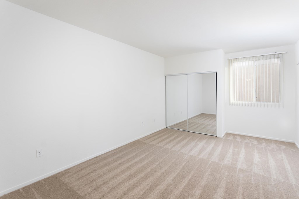 A room with a carpeted floor and a sliding door. at La Jolla Crossroads Apartments, San Diego, CA