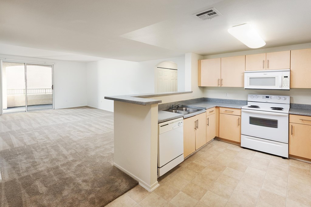 A kitchen with a white stove top oven and white dishwasher. at La Jolla Crossroads Apartments, California