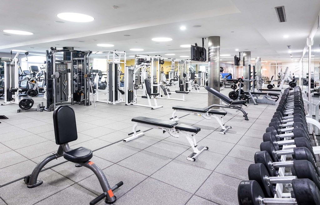 A spacious gym with a variety of equipment including treadmills, weight machines, and dumbbells. at La Jolla Crossroads Apartments, San Diego