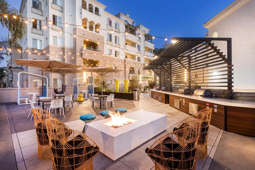 A patio with a fire pit surrounded by chairs and tables. at La Jolla Crossroads Apartments, California