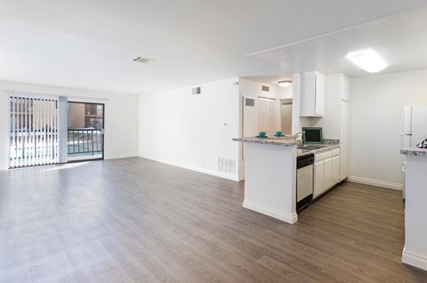 A spacious kitchen and living room with white cabinets and a wooden floor.